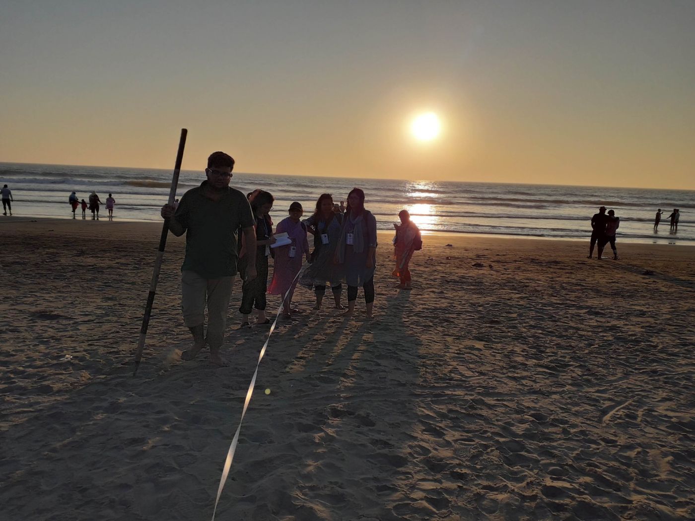 Beach profiling with a ranging pole and tape at sunset